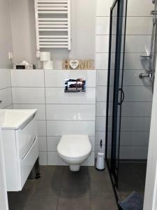 a white bathroom with a toilet and a shower at Apartamenty Zatorze in Leszno