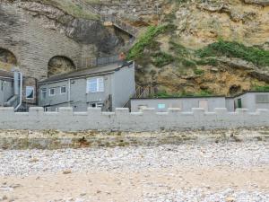 ein Gebäude vor einem Berg neben einer Mauer in der Unterkunft Sea View Cottage in South Shields