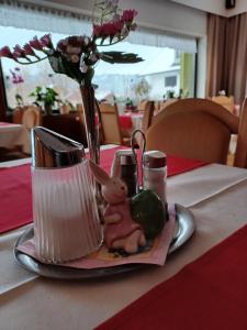 einen Tisch mit einer Vase mit einem Kaninchen und Blumen in der Unterkunft Retro Hotel Igelheim in Bad Mitterndorf