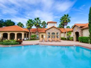 uma grande piscina em frente a uma casa com palmeiras em Disney Memories at Tuscana Resort em Kissimmee