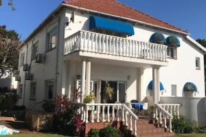 a white house with a balcony and stairs at Sagelands for business travel & family getaways in Durban