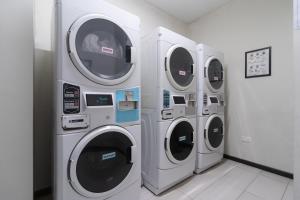 three washing machines in a laundry room next to a wall at Louis Kienne Serviced Residences - Havelock in Singapore
