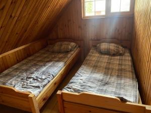 two twin beds in a wooden cabin with a window at Aga Kotkowo in Łukta