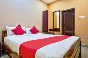 1 dormitorio con 1 cama grande con almohadas rojas en Sri Abirami Inn, en Pondicherry