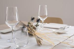 una mesa con dos copas de vino y un arreglo floral en Hub Hotel en Gubbio