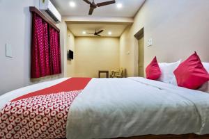 um quarto com uma cama grande e almofadas vermelhas e brancas em Sri Abirami Inn em Pondicherry