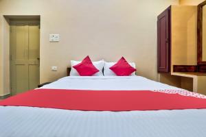 um quarto com uma cama grande e almofadas cor-de-rosa em Sri Abirami Inn em Pondicherry