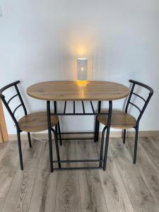 a wooden table with two chairs and a table with a light at Apartamenty Zatorze in Leszno