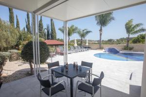 a patio with a table and chairs and a pool at Villa Margarita in Protaras