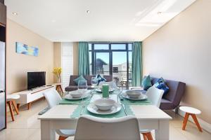 a dining room and living room with a table and chairs at A Modern unit, self checkin, restaurants and shops below in Cape Town