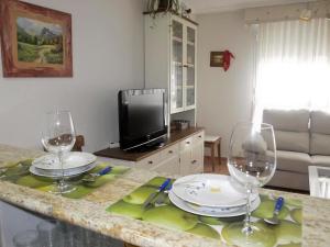 un tavolo con due bicchieri da vino e una televisione di Apartamento Alameda Ezcaray, piscina y ascensor a Ezcaray