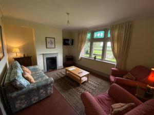 sala de estar con sofá, sillas y chimenea en Thornton Manor - Holiday Cottages and Apartments en Heswall
