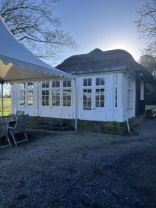 een wit gebouw met een tent en twee stoelen bij Thornton Manor - Holiday Cottages and Apartments in Heswall