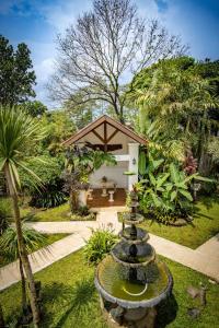 a garden with a fountain in front of a house at Family Hotel Gradia 1 in Batu