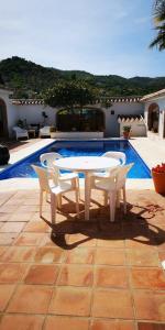 een witte tafel en stoelen naast een zwembad bij Casa Ana Maria in Guaro