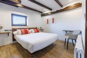 1 dormitorio con 1 cama blanca grande y escritorio en Casa Rural Arotzenea, en Hondarribia