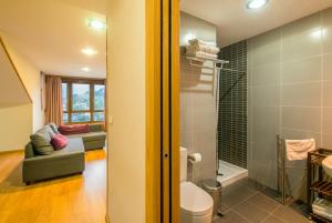 a bathroom with a toilet and a couch in a room at Apartamentos Camparina in Llanes