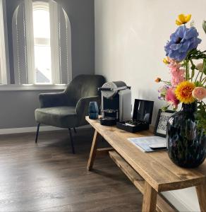 een woonkamer met een tafel met een vaas met bloemen bij Hotel Tholen in Tholen