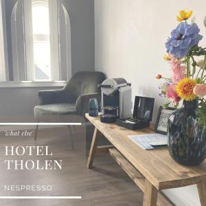 Hotel Tholen في ثولين: غرفة معيشة مع طاولة مع إناء من الزهور