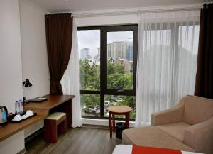 um quarto de hotel com uma janela com uma cadeira e uma secretária em Luckful Hotel em Hanói
