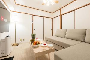 uma sala de estar com um sofá e uma tigela de fruta numa mesa em River Side Namba 600 em Osaka
