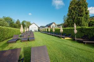 a row of lounge chairs and umbrellas on a lawn at Feel Good Apartments in Krumpendorf am Wörthersee