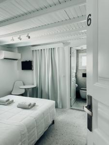 a white bedroom with a bed and a bathroom at Alana Mykonos in Mikonos