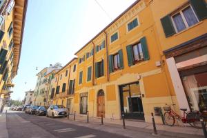 een geel gebouw op een straat met geparkeerde auto's bij Case VR Holiday Canter House in Verona
