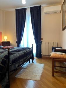 1 dormitorio con 1 cama y una ventana con cortinas azules en Tuscan Room en San Quirico dʼOrcia