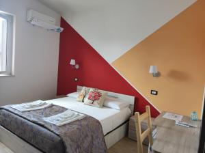 1 dormitorio con cama y pared roja en B&B Lara Santola en Corato