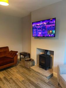 a living room with a fireplace and a tv on the wall at The Garden House, Necarne, Irvinestown in Irvinestown