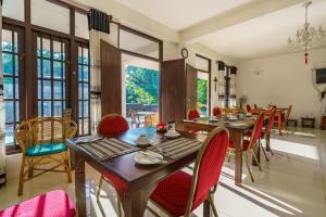 a dining room with red chairs and tables and windows at Abundia Unawatuna in Unawatuna