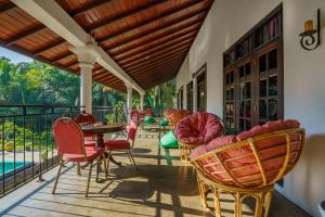 eine Veranda mit Stühlen, Tischen und einem Pool in der Unterkunft Abundia Unawatuna in Unawatuna