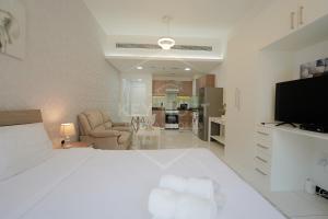 a white bedroom with a large bed and a living room at KeyHost - Crystal Residence JVC - K160 in Dubai