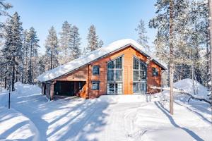 a log cabin in the snow with trees at Villa Amiraali Levi in Levi