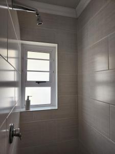 a bathroom with a window and a shower at Schnehage Self Catering in Bloemfontein