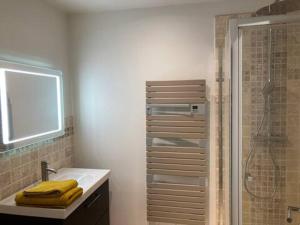 La salle de bains est pourvue d'un lavabo, d'une douche et de serviettes jaunes. dans l'établissement maison de 156m2, 5 chambres et jardin à Malakoff, à Malakoff