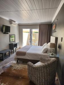 a bedroom with a bed and a desk and a television at Schnehage Self Catering in Bloemfontein