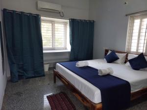 1 dormitorio con 2 camas y cortinas azules en Deccan Stay, en Hyderabad