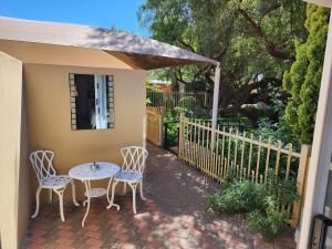 patio ze stołem, krzesłami i ogrodzeniem w obiekcie Schnehage Self Catering w mieście Bloemfontein
