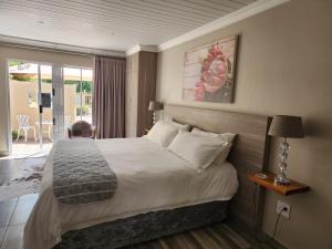 a hotel room with a bed and a balcony at Schnehage Self Catering in Bloemfontein