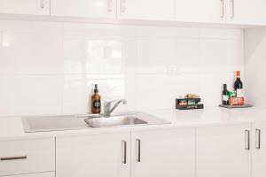 a kitchen with white cabinets and a sink at Quality Apartments Banksia Albany in Albany