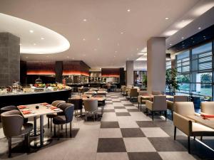 a restaurant with tables and chairs and a checkerboard floor at Pullman Miri Waterfront in Miri