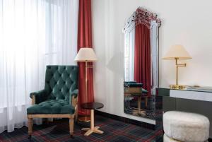 a room with a green chair and a mirror at Wyndham Garden Donaueschingen in Donaueschingen