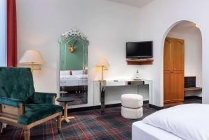 a hotel room with a bed and a chair and a television at Wyndham Garden Donaueschingen in Donaueschingen