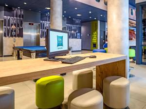 a desk with a computer and stools in a store at ibis budget Sorocaba in Sorocaba