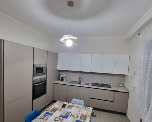 uma cozinha com armários brancos, uma mesa e um lavatório em Realmonte Casa vacanze Realbeach em Realmonte