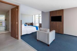 a hotel room with a bed and a chair and a television at Wyndham Puebla Angelopolis in Puebla