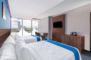 a hotel room with two beds and a television at Wyndham Puebla Angelopolis in Puebla
