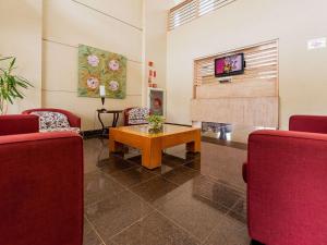 a waiting room with red chairs and a table at Ibis Styles Campinas Alphaville in Campinas